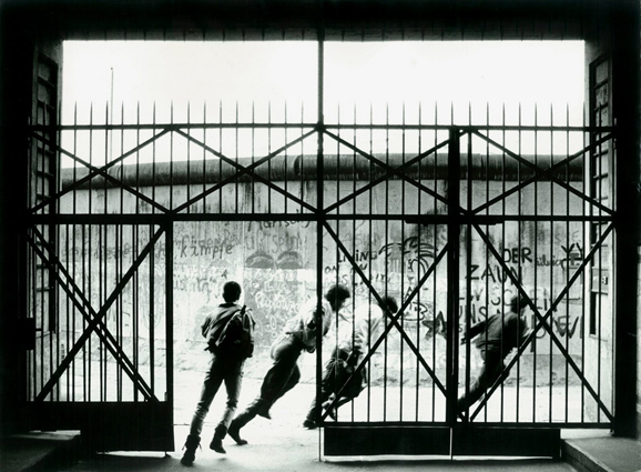 schwarz-weiß Fotografie Jungen, die aus einem Gittertor laufen, von Wolfgang Krolow