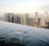 A man floats in the 57th-floor swimming pool of the Marina Bay Sands Hotel, with the skyline of the Singapore financial district behind him. 2013 Paolo Woods & Gabriele Galimberti—INSTITUTE